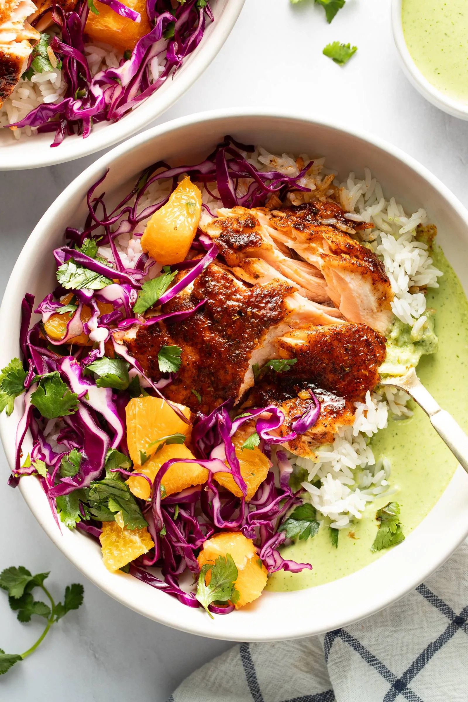 Chipotle salmon bowl with orange salsa, purple cabbage, rice, and green sauce