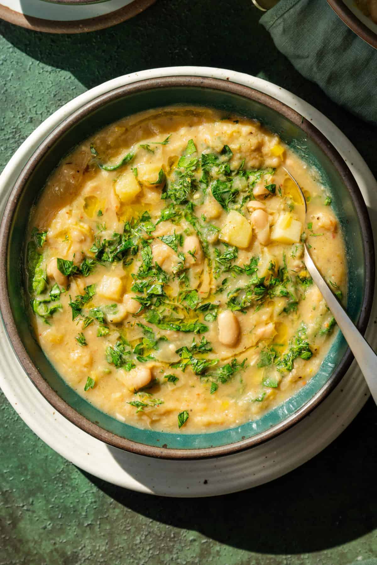 Creamy vegan potato leek soup with herbs on top