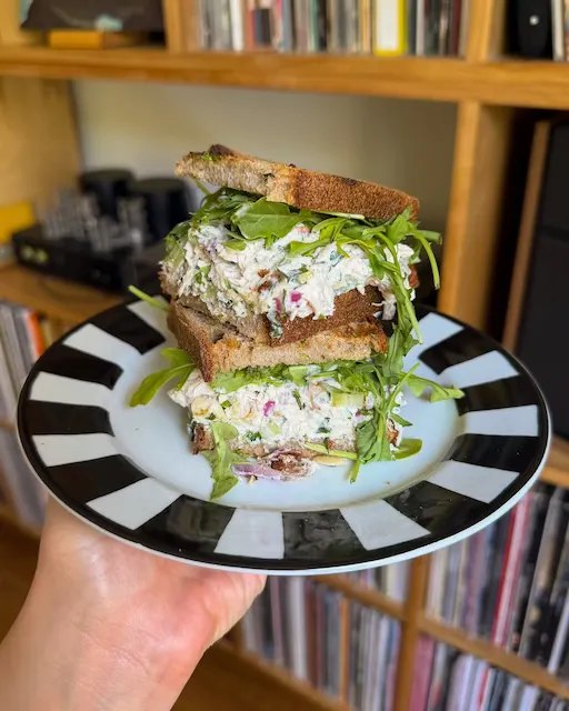 Date and almond chicken salad sandwich stacked on a striped plate