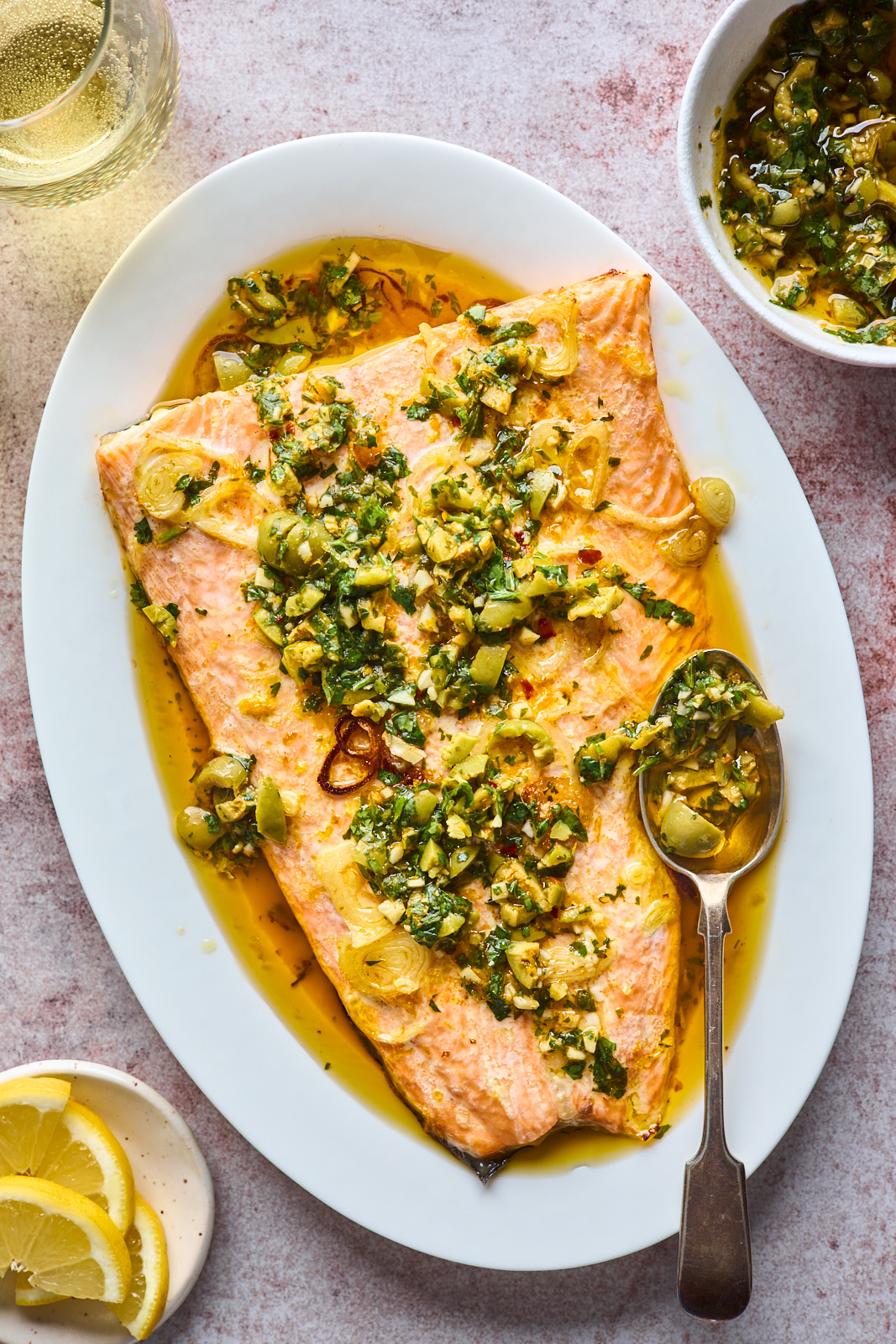 Roasted salmon topped with green olive salsa verde in a baking dish